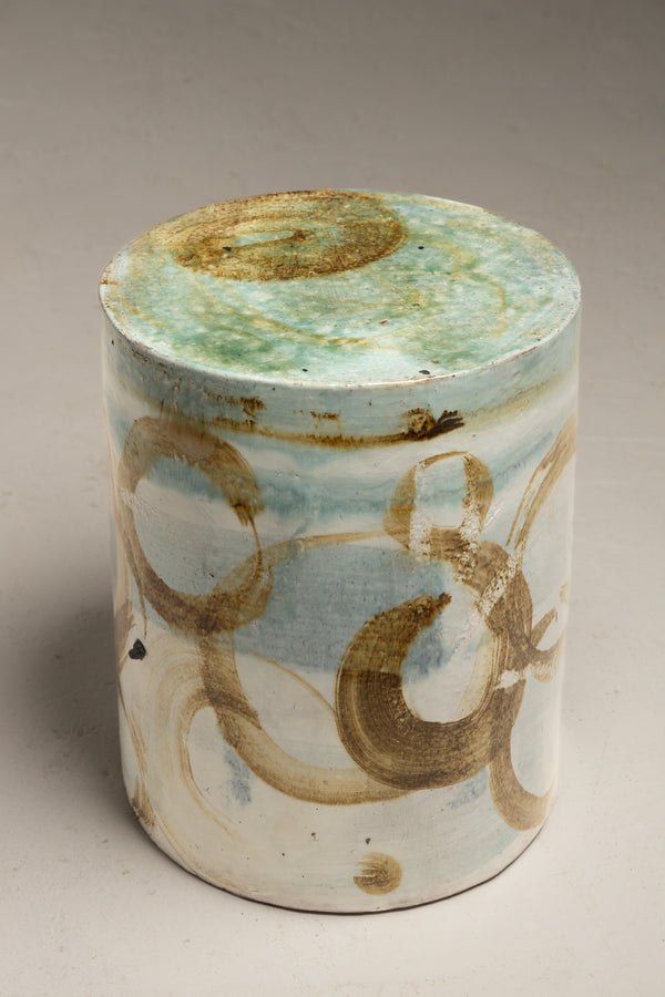 Elevate your space with our ceramic stool, boasting a smooth surface and adorned with artistically painted golden brown brush swirls, accentuated by broad strokes of aqua green runny glaze in an abstract style - GJLJLK